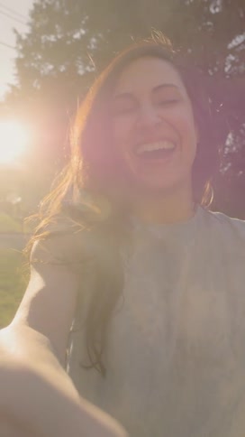 A woman laughs while on a video call outdoors