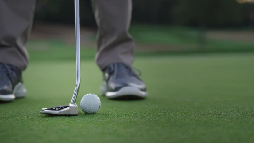Man with grey pants and sneakers plays golf