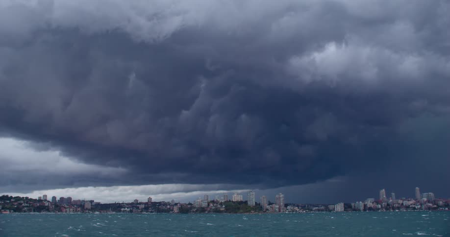Huge storm clouds linger above the ocean and large city located along the nearby coastline