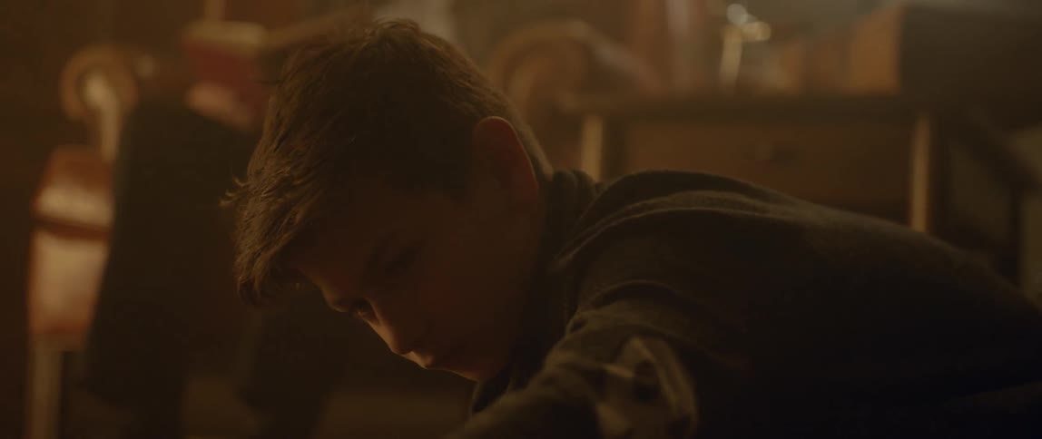 A young boy plays with a toy near a fireplace