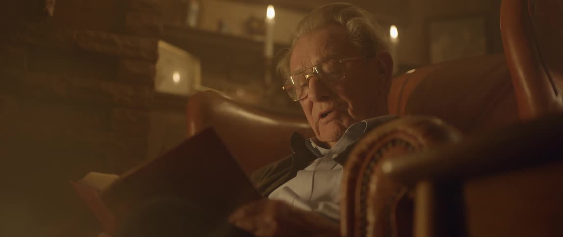 An elderly man reading a book out loud