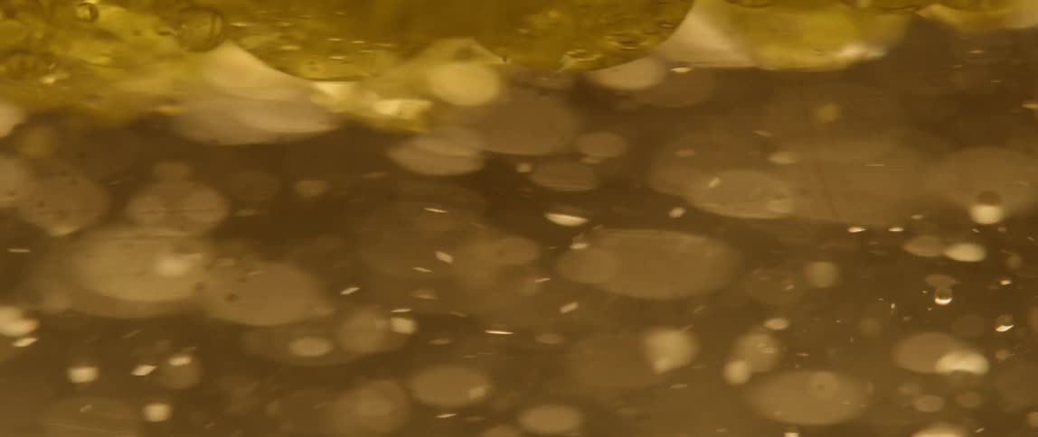 Small bubbles swirl and move in yellow liquid