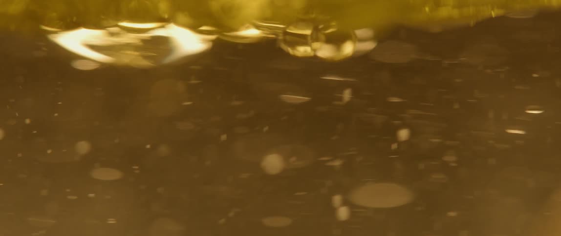 Bubbles move around in a thick yellow liquid
