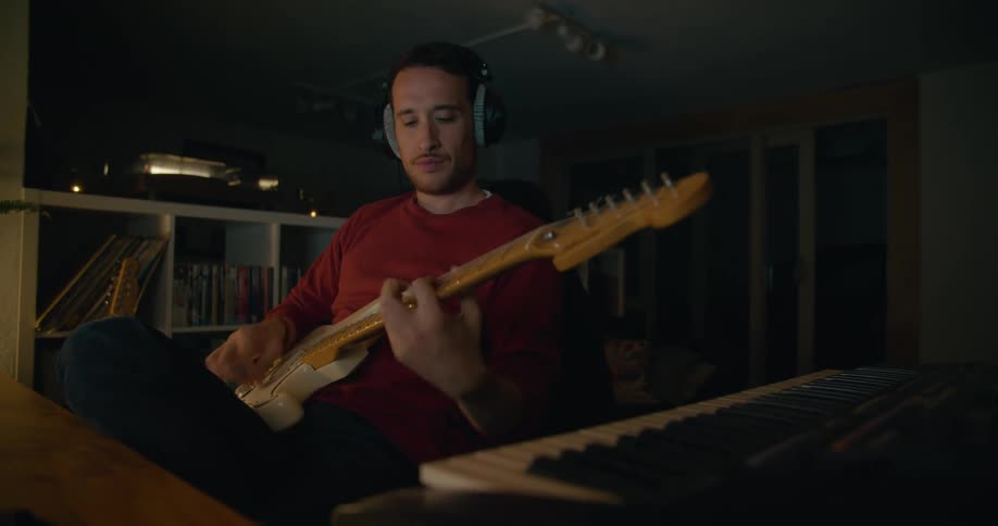 A man is playing the guitar in the dark room