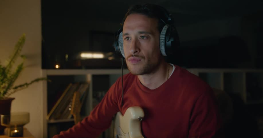 A man strums a little on a guitar then logs something in a computer