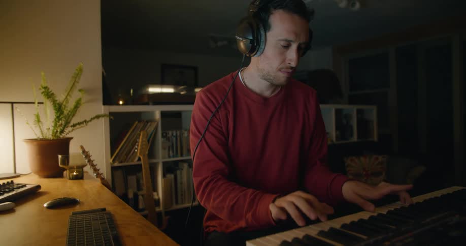 Man plays piano keyboard sitting near table with computer