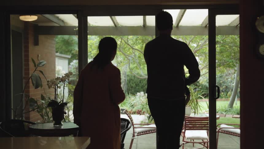 Couple walk out onto patio to greet man walking up path