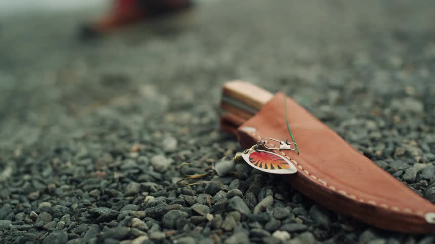 Person walks away from knife laying on ground in leather sheath