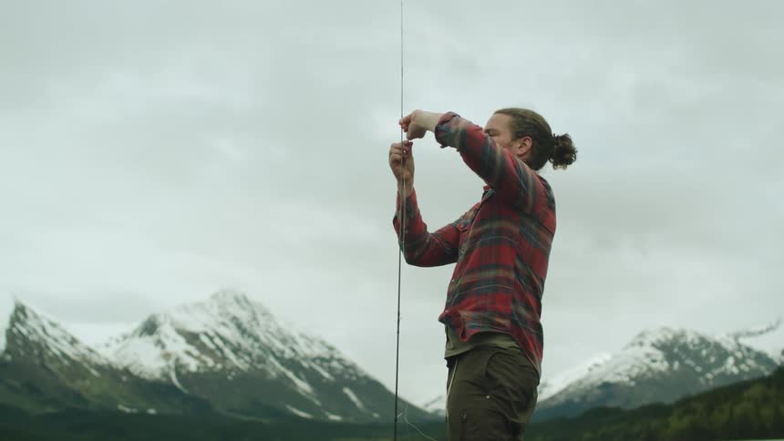 A man is attaching a fishing line to his pole