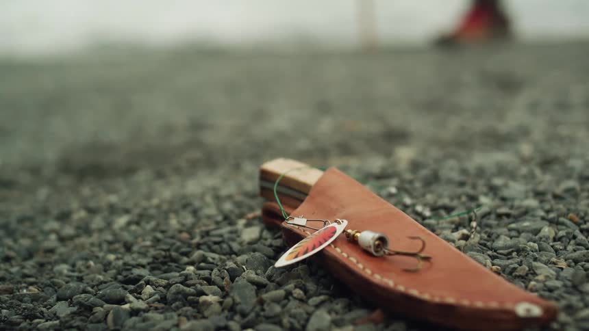 A knife and a fishing hook on the ground