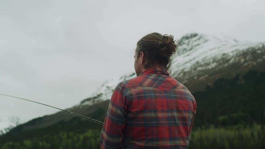 A man is walking towards the lake with a fishing pole