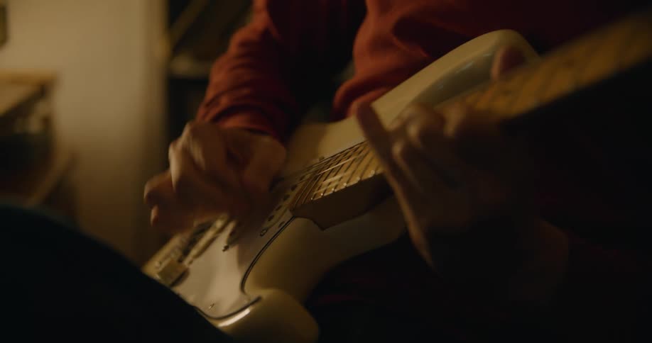 A man is playing the guitar in the dark room