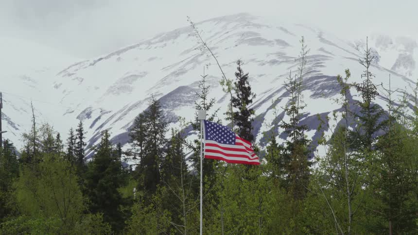 An american flag blows in the wind outside a nature preserve near a mountain range