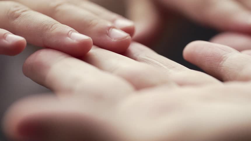 A child runs its hands along the palms of an adult