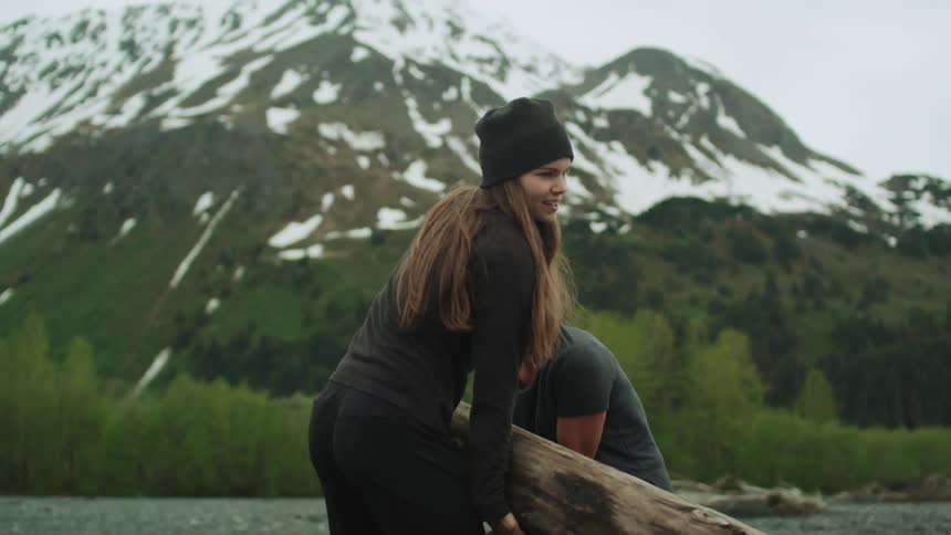 A woman rushes to help another woman trying to move a large log