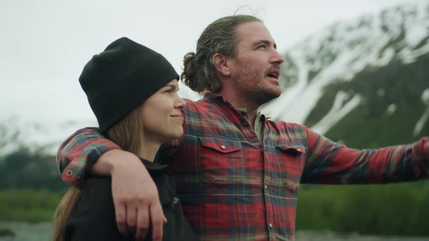 Couple standing near a lake on the snow covered mountains