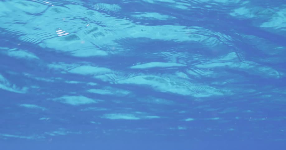 The surface of the clear blue water ripples and waves