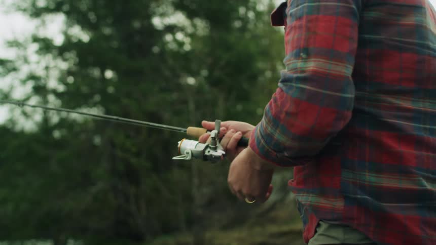 A man swings his arms casting his fishing line into the water