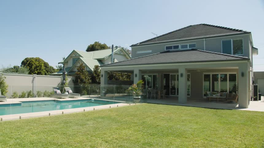 Backyard of a house with a pool and green trimmed lawn
