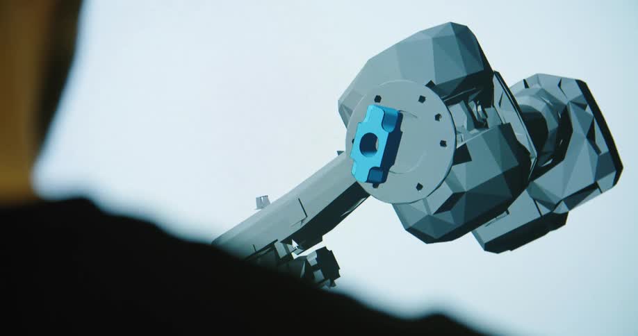 A man in the room looking at a screen of an animated robot arm