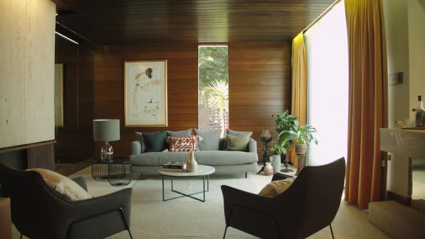 Window near large framed art and gray sofa shows a palm tree