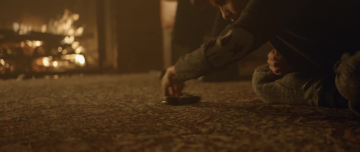 A young boy plays with a toy near a fireplace