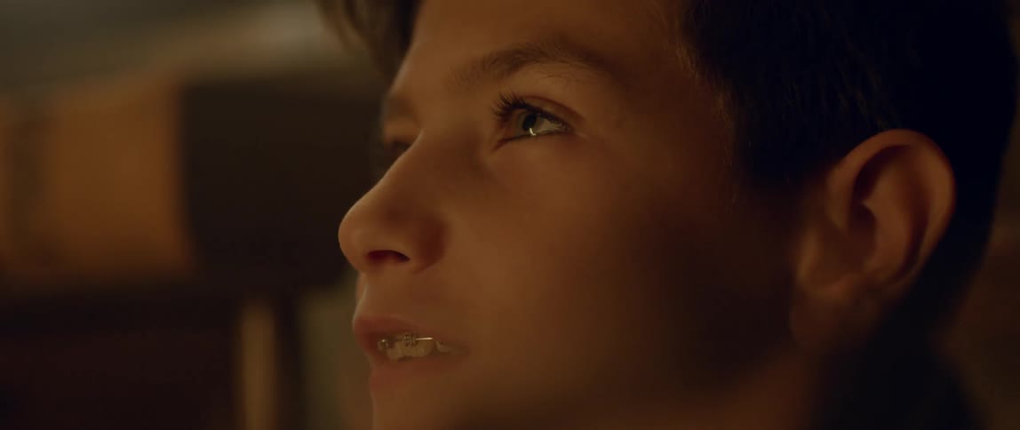 A boy blinks and smiles as he looks up