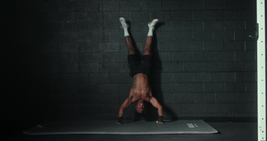 A man doing handstand pushups in a room