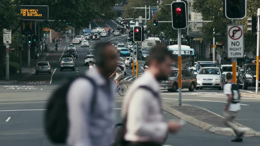 Pedestrians bicycles and cars crossing and driving on the busy city street