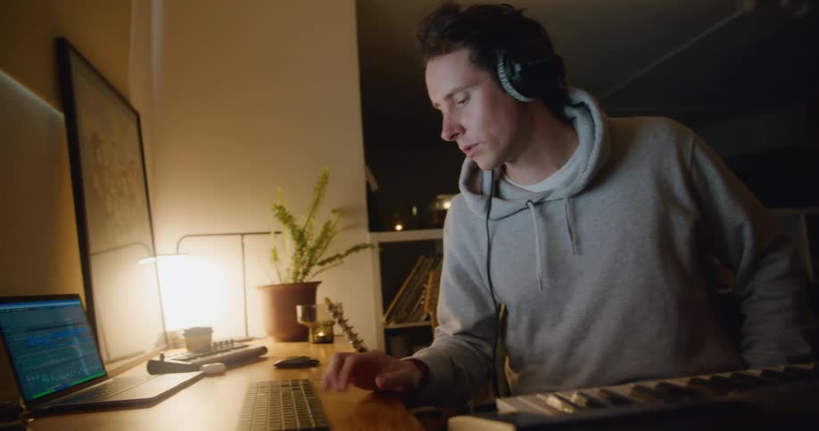 A man plays on the keyboard then looks over to the computer