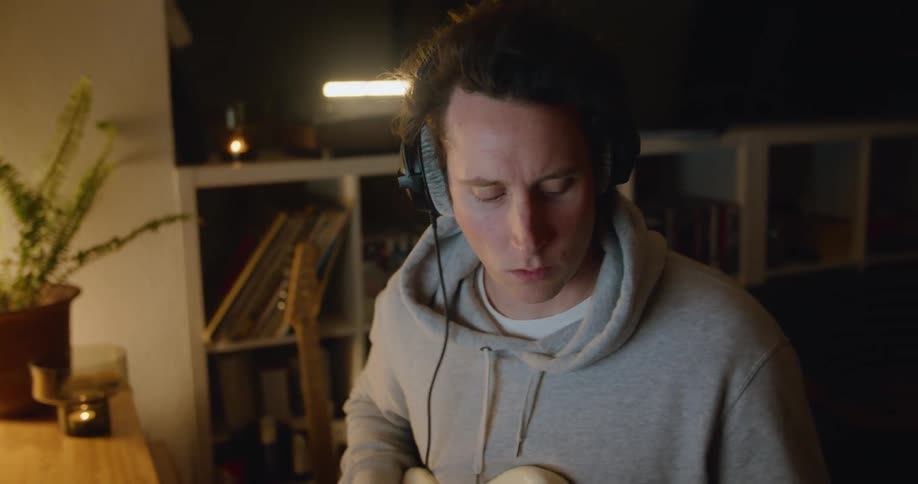 A man uses recording software on his laptop to record himself playing guitar