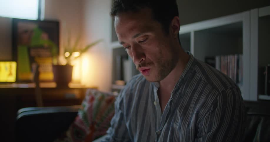 A man draws on his tablet while sitting on the couch at home
