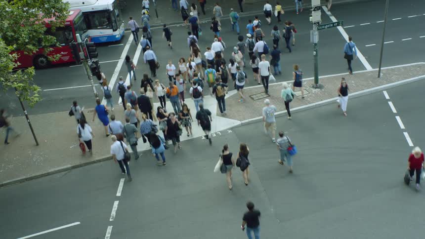 Several people cross the street at a light in a city