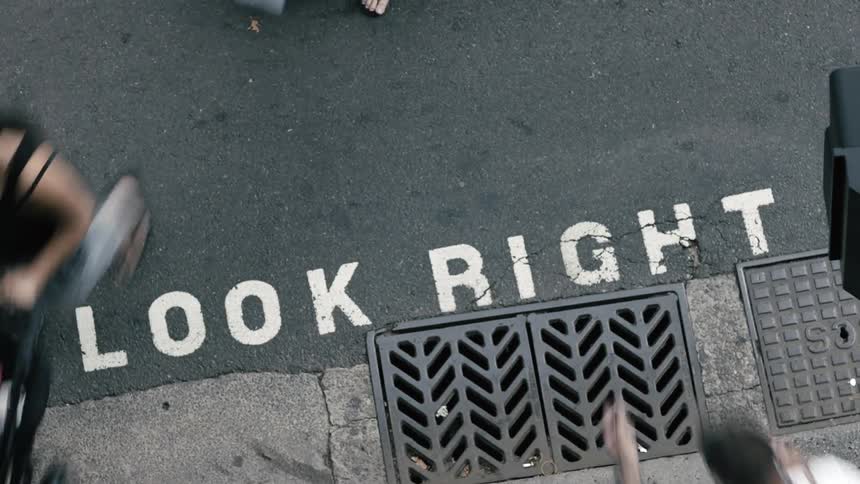 An overhead timelapse view of pedestrians and a crosswalk in a citys downtown area during the day