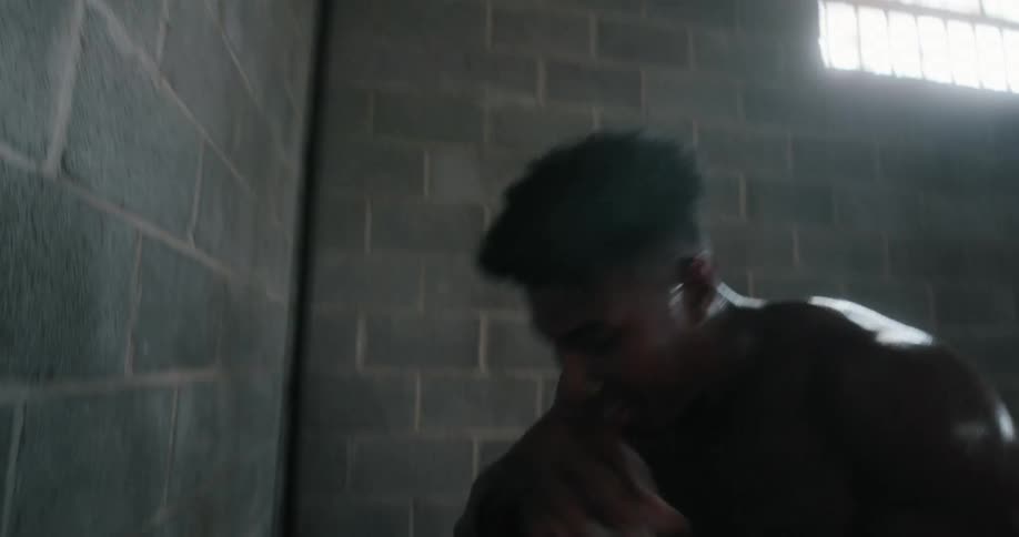 Shirtless muscular man pushes against the wall and rests in the gym