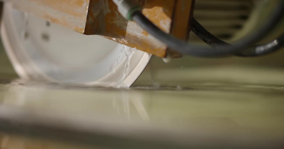 Water drips from an electric saw sitting on a flooded table in a warehouse