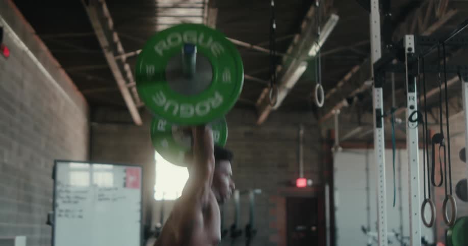 A man is lifting a heavy barbell with weights in a gym