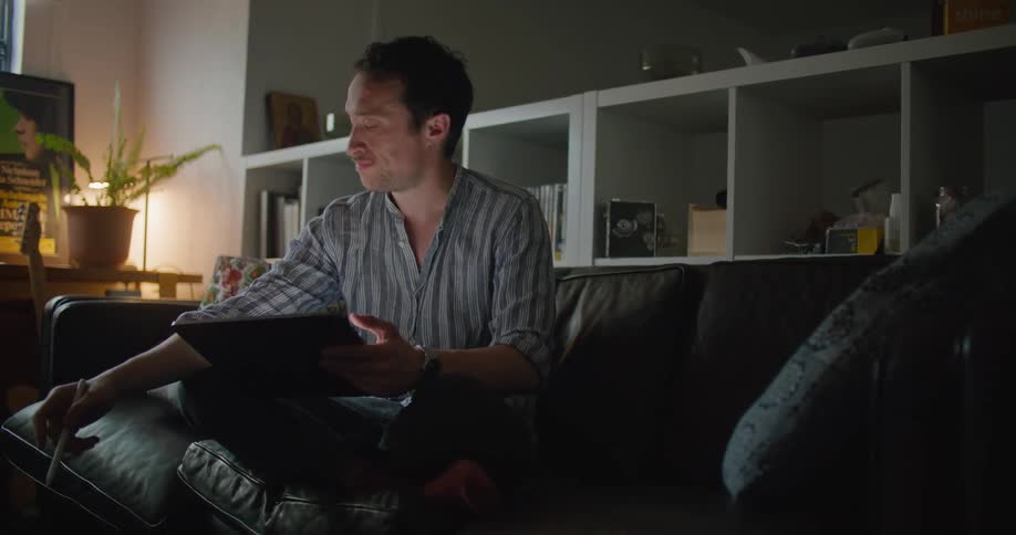 Man sitting on the couch working on a tablet at home