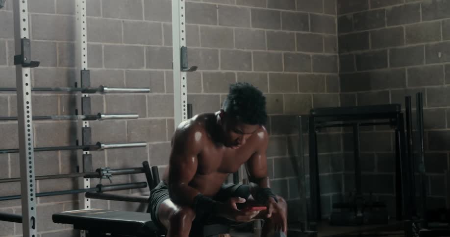 A sweaty man sits down to look at his phone