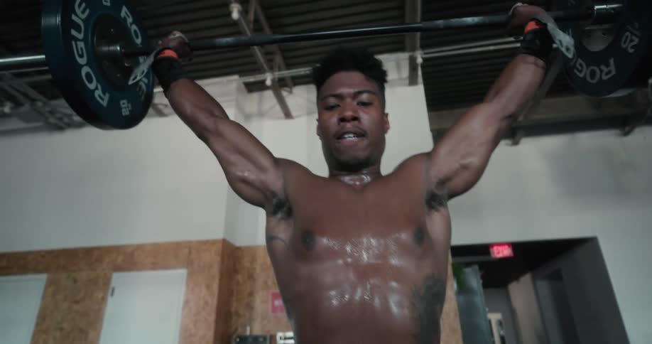 Strong shirtless muscular man lifting weights on a gym