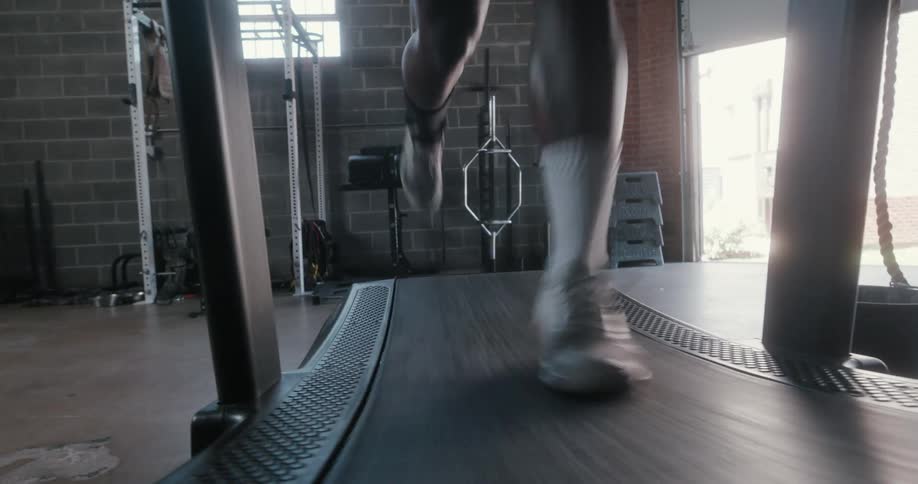 The legs of a man as he runs on a treadmill
