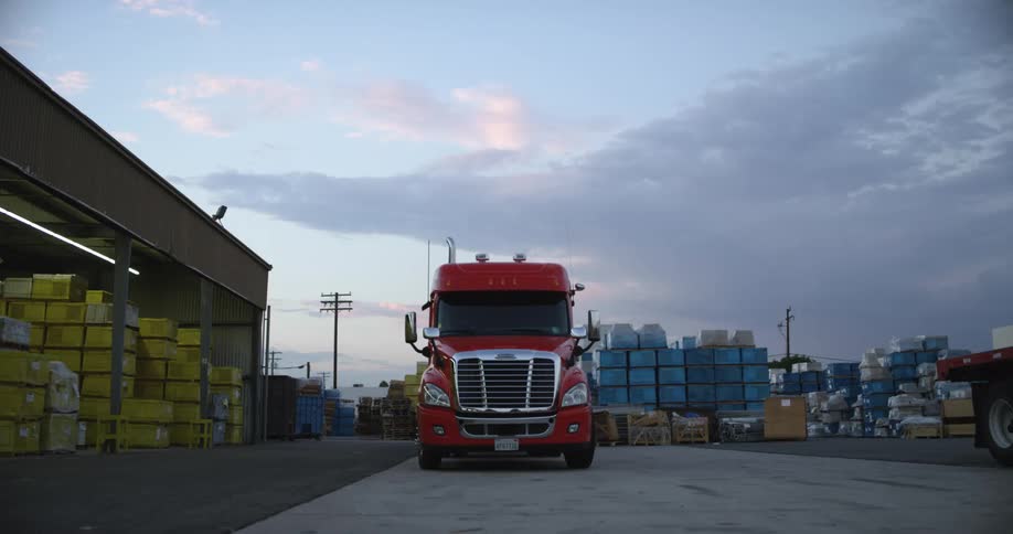 A truck next to a building with the sky and clouds in the background