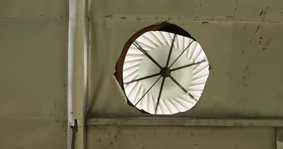 A fan is spinning in a hole in a wall