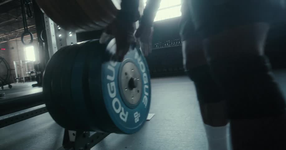 A man carries a weight through a gym to place it on its holding rack