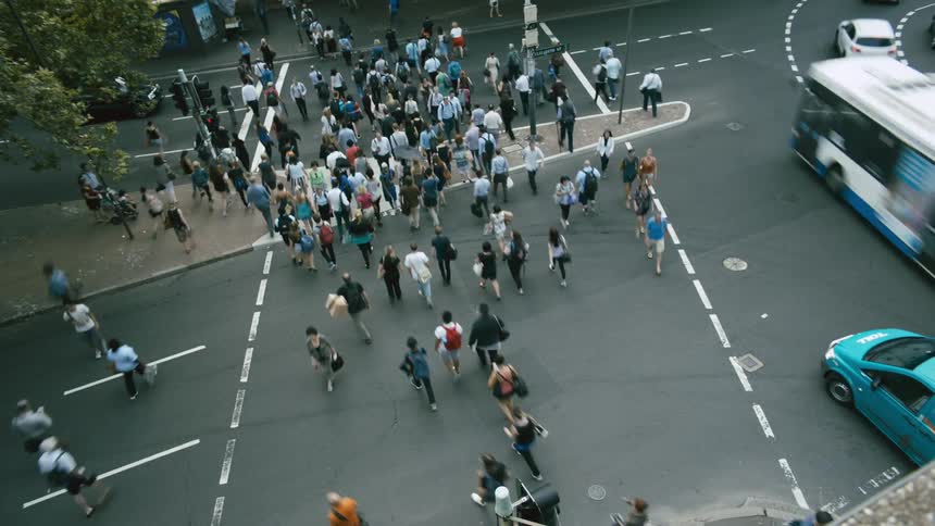 A group of people that are walking around crossing a street