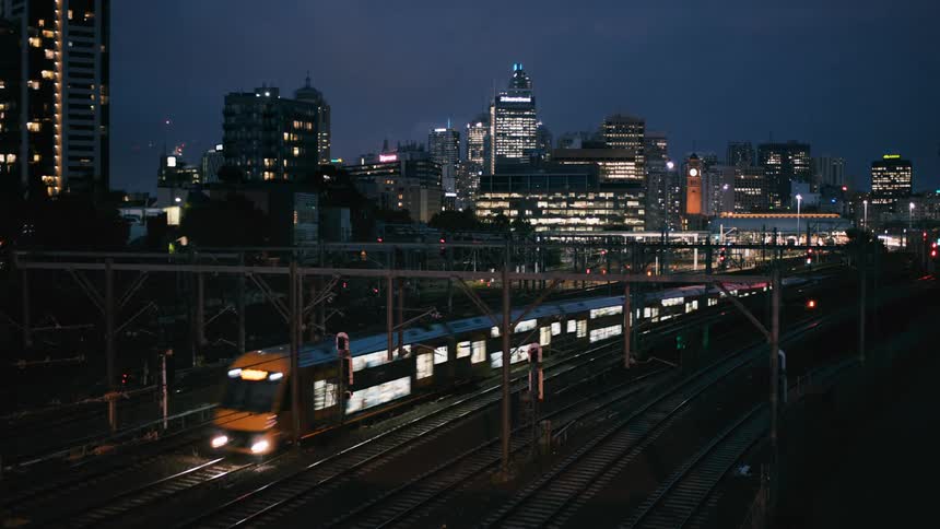 Illuminated high rise buildings and trains running on tracks