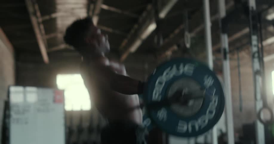 A man does powerlifting in the gym as he lifts weight over his head