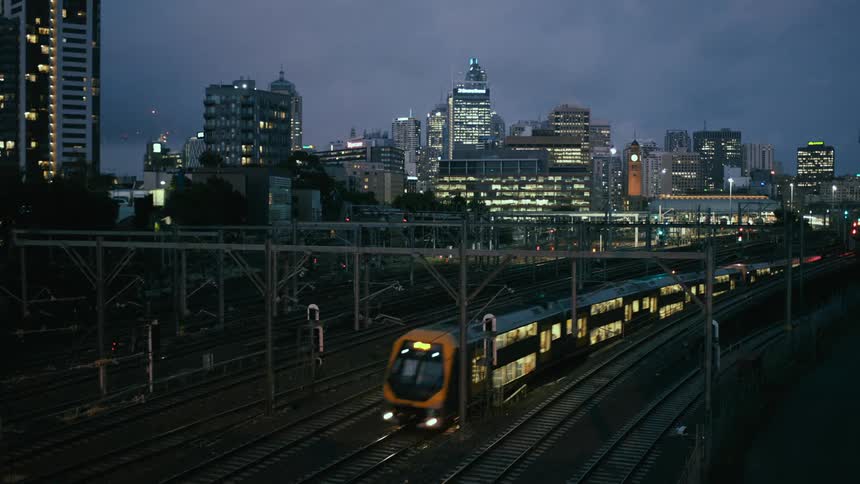 A train travels along a track through a metropolis on at night
