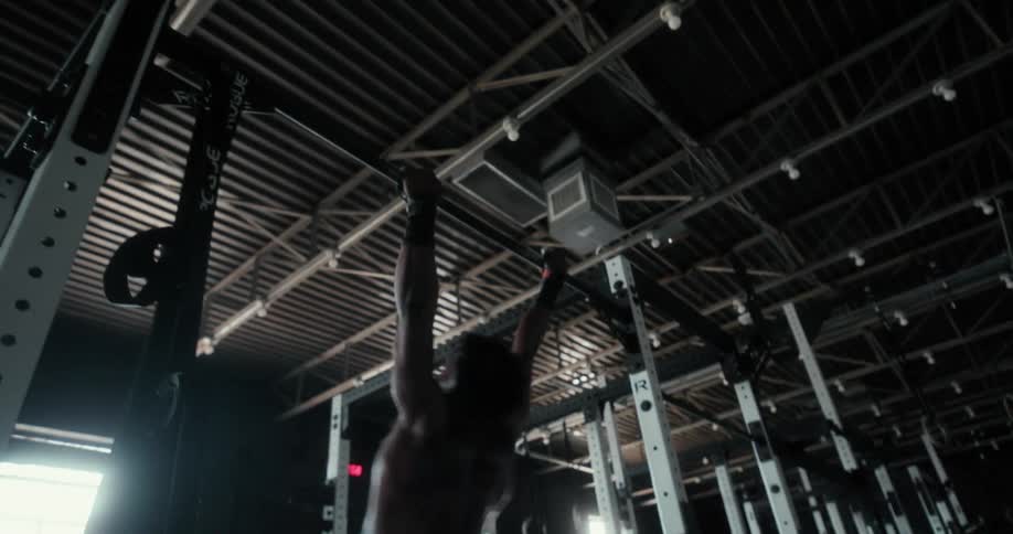A man jumps up and grabs a bar and pulls himself up above it