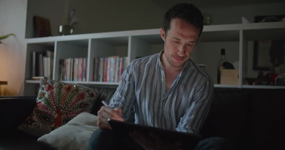 A man is drawing on a tablet when he suddenly looks up